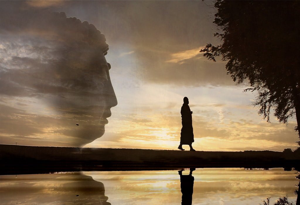 A creative double exposure image featuring the silhouette of a person standing by a water body at sunset, superimposed with the profile of a large statue's head, resulting in a reflective and dreamlike quality.
