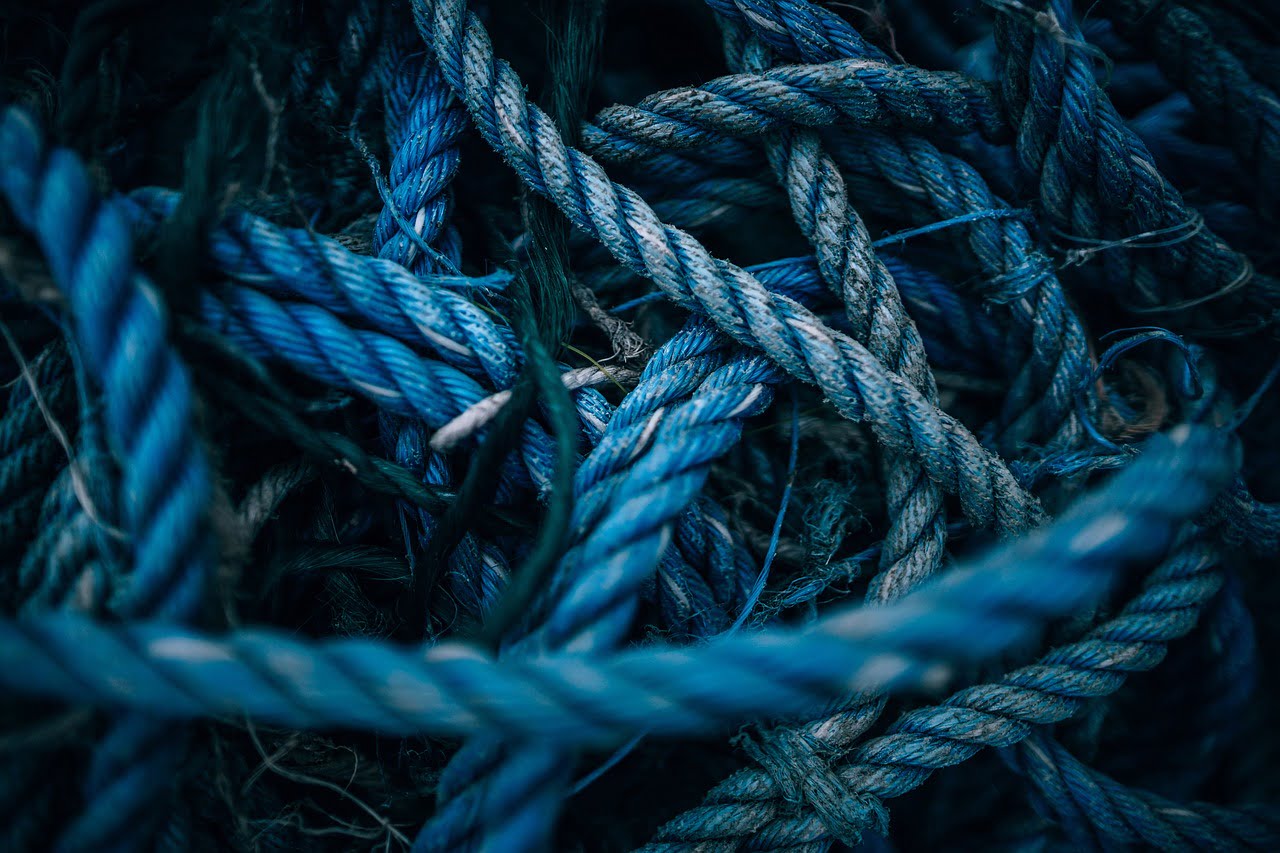 Close-up of intertwined blue and natural colored ropes with a focus on the texture and pattern.