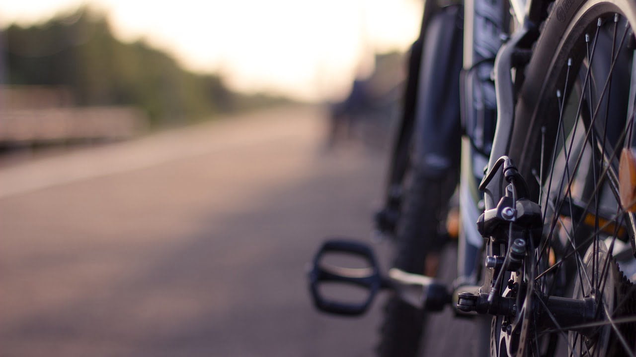 A close-up shot of bicycle wheels aligned on a street, with a shallow depth of field blurring the background.