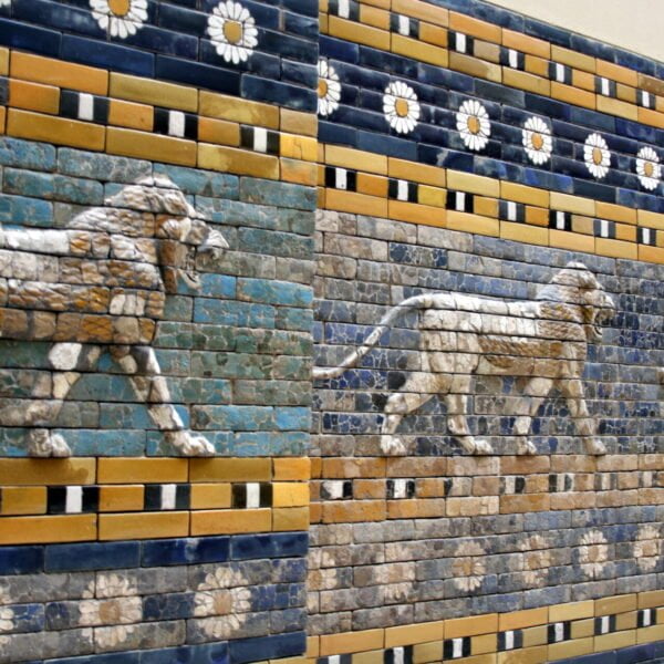Ancient Mesopotamian lion relief tiles from the Ishtar Gate, showing a row of striding lions on a blue glazed brick wall with floral and geometric patterns.